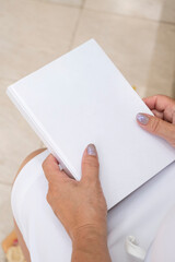 Obraz premium unrecognizable woman holding blank magazine for mockup design, sitting on bench