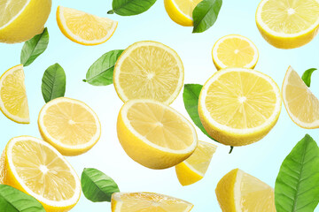 Fresh juicy lemons and green leaves falling on light blue background