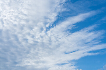 Beautiful fluffy white clouds drift across a clear blue sky, painting a breathtaking summer cloudscape
