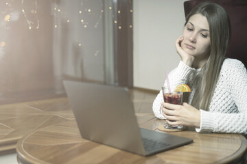 Young girl browsing the Internet at the cafe in the evening