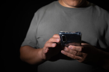 A person holds a smartphone, illuminated by its screen in the darkness