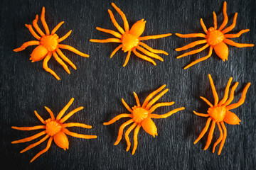 Fake orange spiders on a black background. nice Background for halloween for posters or flyers.