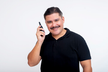 A middle-aged man in a black t-shirt smiling while talking on a two-way radio. Isolated on a white background.