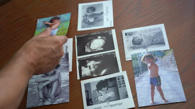Father looks at family memory album photos with the birth of newborn son , memories of childhood and growth of the child year after year. Dad and son lifestyle , parent remembers the child's childhood