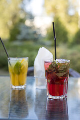 Two drinks on a table, one is a yellow drink and the other is a red drink
