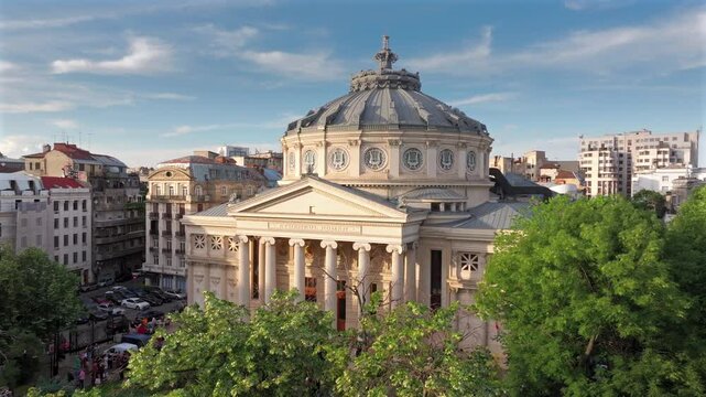 Romanian Atheneum in Bucharest during a summer sunset. Aerial 4k video of this amazing landmark historical building from Bucharest, Romania, on Victoriei Avenue (Calea Victoriei). Travel to Romania.