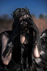 Naklejka premium Goddess of death with black wings on a dried field