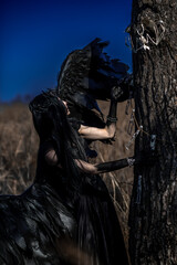 Naklejka premium Goddess of death with black wings on a dried field