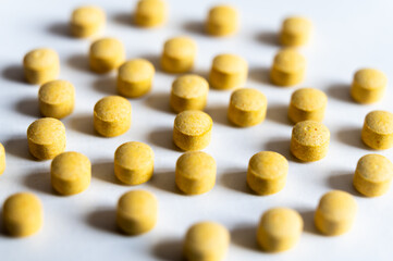 Medical tablets, placed next to each other on a white surface. Therapies, medicines and supplements.