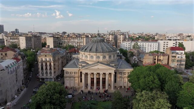 Romanian Atheneum in Bucharest during a summer sunset. Aerial 4k video of this amazing landmark historical building from Bucharest, Romania, on Victoriei Avenue (Calea Victoriei). Travel to Romania.