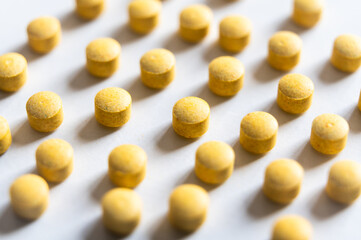 Medical tablets, placed next to each other on a white surface. Therapies, medicines and supplements.