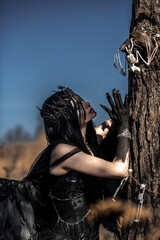 Naklejka premium Goddess of death with black wings on a dried field
