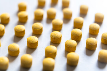 Medical tablets, placed next to each other on a white surface. Therapies, medicines and supplements.