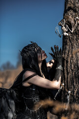 Naklejka premium Goddess of death with black wings on a dried field