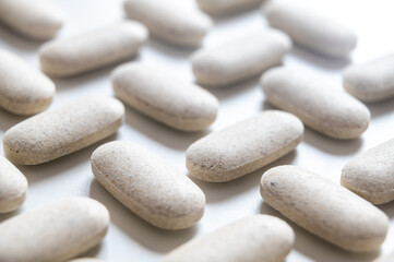 Medical tablets, placed next to each other on a white surface. Therapies, medicines and supplements.