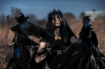 Goddess of death with black wings on a dried field