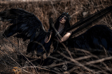 Goddess of death with black wings on a dried field