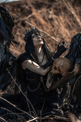 Goddess of death with black wings on a dried field