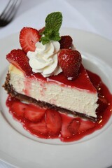 A decadent slice of cheesecake topped with fresh strawberries and a dollop of whipped cream