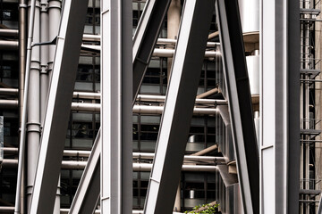 A close-up of steel beams creating a geometric pattern in a modern urban architectural structure. The composition showcases industrial design and engineering precision.