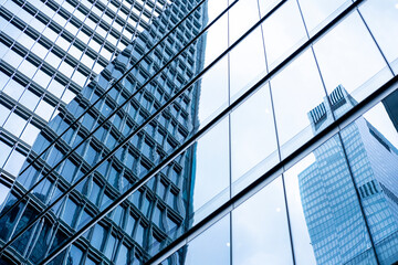 A reflective glass skyscraper mirrors the urban skyline in the background. The image captures the essence of modern city life with high-rise buildings and dynamic architecture.
