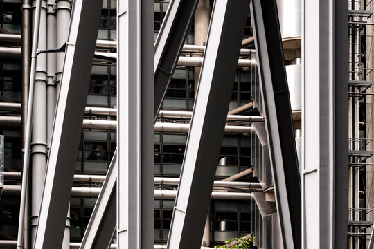 A close-up of steel beams creating a geometric pattern in a modern urban architectural structure. The composition showcases industrial design and engineering precision.