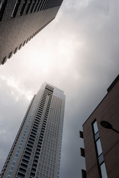 Skyscrapers rise dramatically towards a cloudy sky, creating a powerful and awe-inspiring urban scenery that emphasizes architectural grandeur in modern cities.
