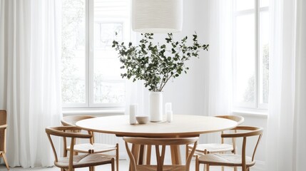 White dining room with a round table, wooden chairs, and a statement pendant light hanging overhead.