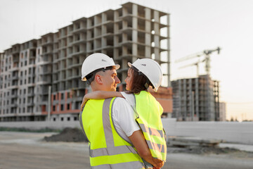 Portrait of a father and daughter in protective helmets on the background of a construction site.