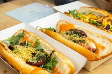 Fresh sandwiches in paper trays on table