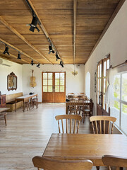 Bright and airy rural countryside home café in vintage rustic theme. Materials full of rustic oak wood, window sheer, antique items, and white stucco walls. Vintage rural European countryside feel.