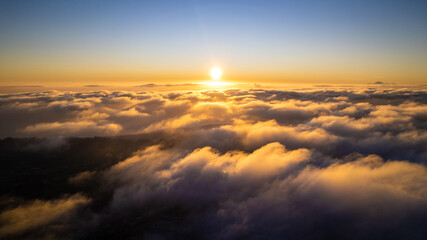 Epic sunrise over the clouds. Flight in the sky with a warm sun rising over the horizon in clouds