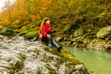 Obraz premium A girl sits on a rock on the river bank