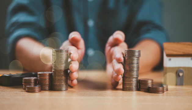 Divorce law and inheritance separation concept. Hand separate saving money, finance, home loan, debt return. Bank business investment. Man separate stack coin, wood house on table. Inherit division