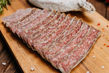 Close-up of sliced dry-cured salami on board, ideal for gourmet food and charcuterie presentations
