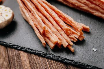 Light meat sticks on board with fresh herbs, garlic, and tomatoes, perfect for food styling needs