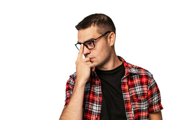 Young man deep in thought wearing glasses and a plaid shirt. A young man with glasses in a plaid shirt touches his face, appearing lost in thought against a plain background.