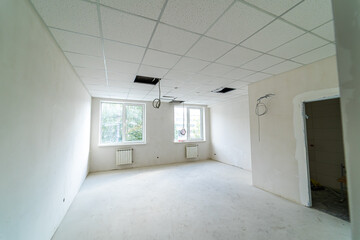 Empty room under renovation with exposed ceiling and natural light. An empty room undergoing renovation, featuring exposed ceiling areas and bright natural light