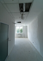 Renovation progress: empty room with exposed ceiling and window. An empty room under renovation with an unfinished ceiling