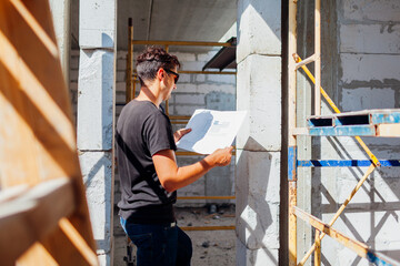 Man architect engineer checking house under construction comparing with blueprint plan on paper....