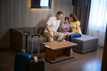 Fototapeta premium Travelers with a little daughter are sitting on cozy sofa