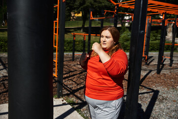 Obraz premium Woman joyfully exercises in a colorful park, embracing her strength and confidence.