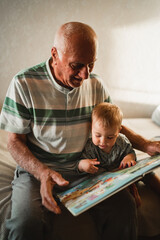 A grandfather and his young grandchild share a tender moment, reading a picture book. The warm...
