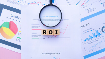 Three wooden cubes with the word ROI on graph sheets, abbreviation for Return on Investment....