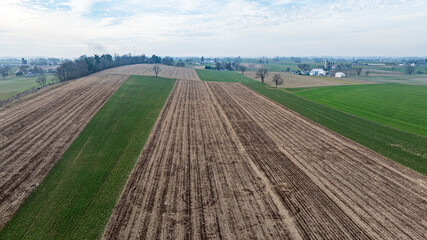 This aerial perspective showcases expansive fields with alternating patches of freshly planted...