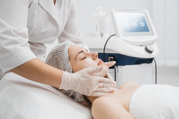 A cosmetologist applies a face cream in a modern beauty clinic, highlighting advanced skincare techniques. Ideal for showcasing premium spa treatments in your advertising.