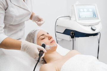 A cosmetologist performs RF lifting and ultrasound facial tightening in a modern salon. This advanced treatment rejuvenates and firms skin, perfect for showcasing effective beauty solutions.