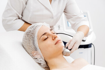 A cosmetologist applies radiofrequency lifting to a young woman in a modern clinic. This advanced...