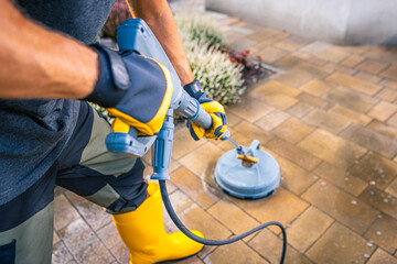 Person Using a Pressure Washer on a Patio in a Residential Backyard During Daytime