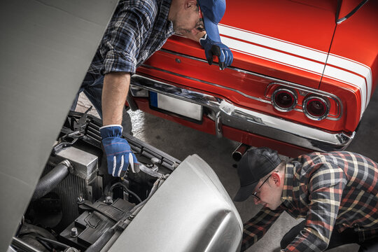 Mechanics Working Together on Classic Cars in a Garage on a Sunny Afternoon
